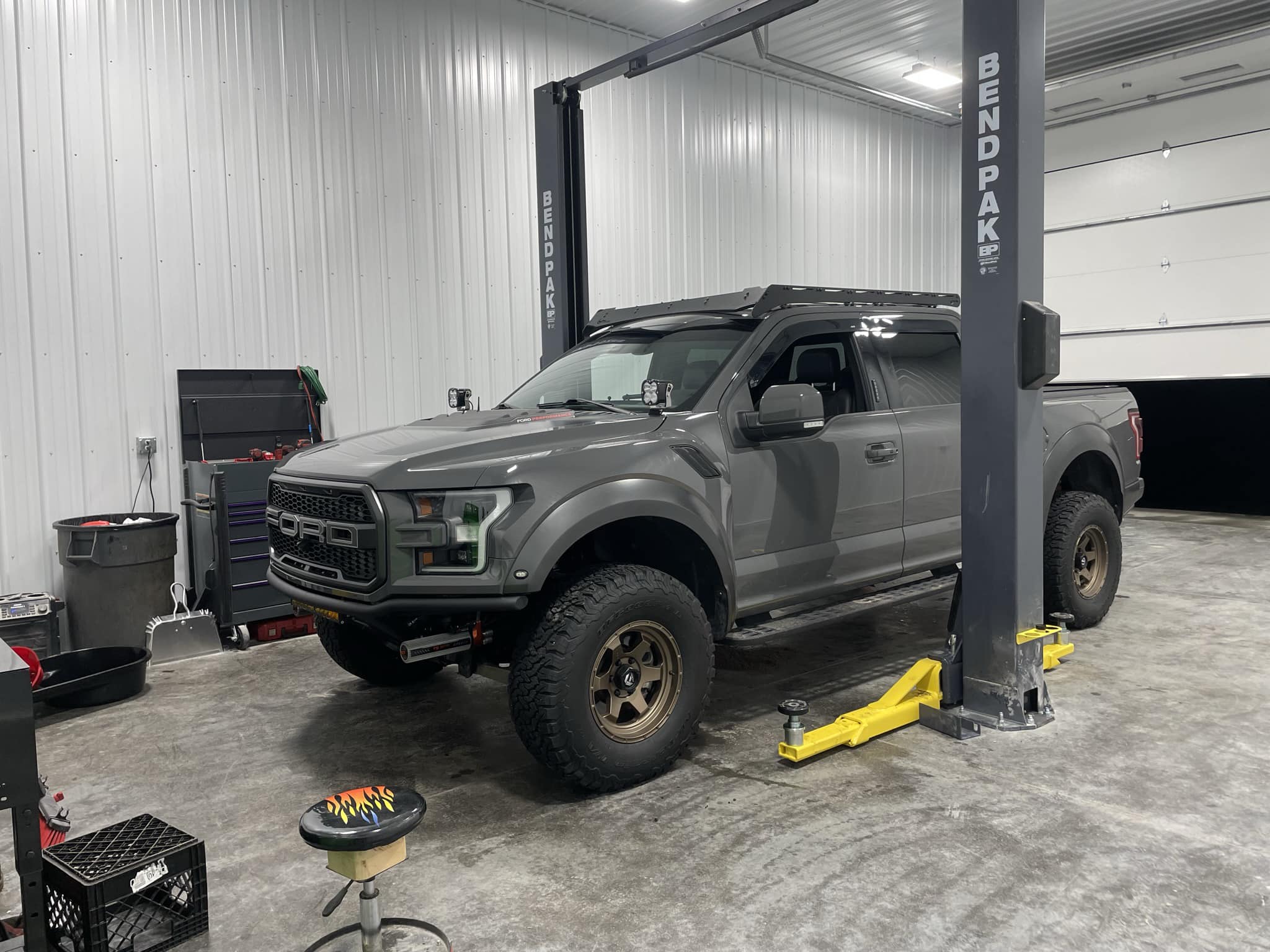Ford Raptor in the shop with custom wheels and roof rack